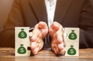 Person separating wooded puzzle blocks with money bags on them
